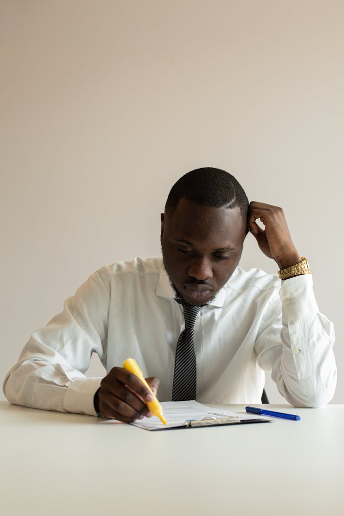 A focused businessman reviews documents at a desk, deep in thought.