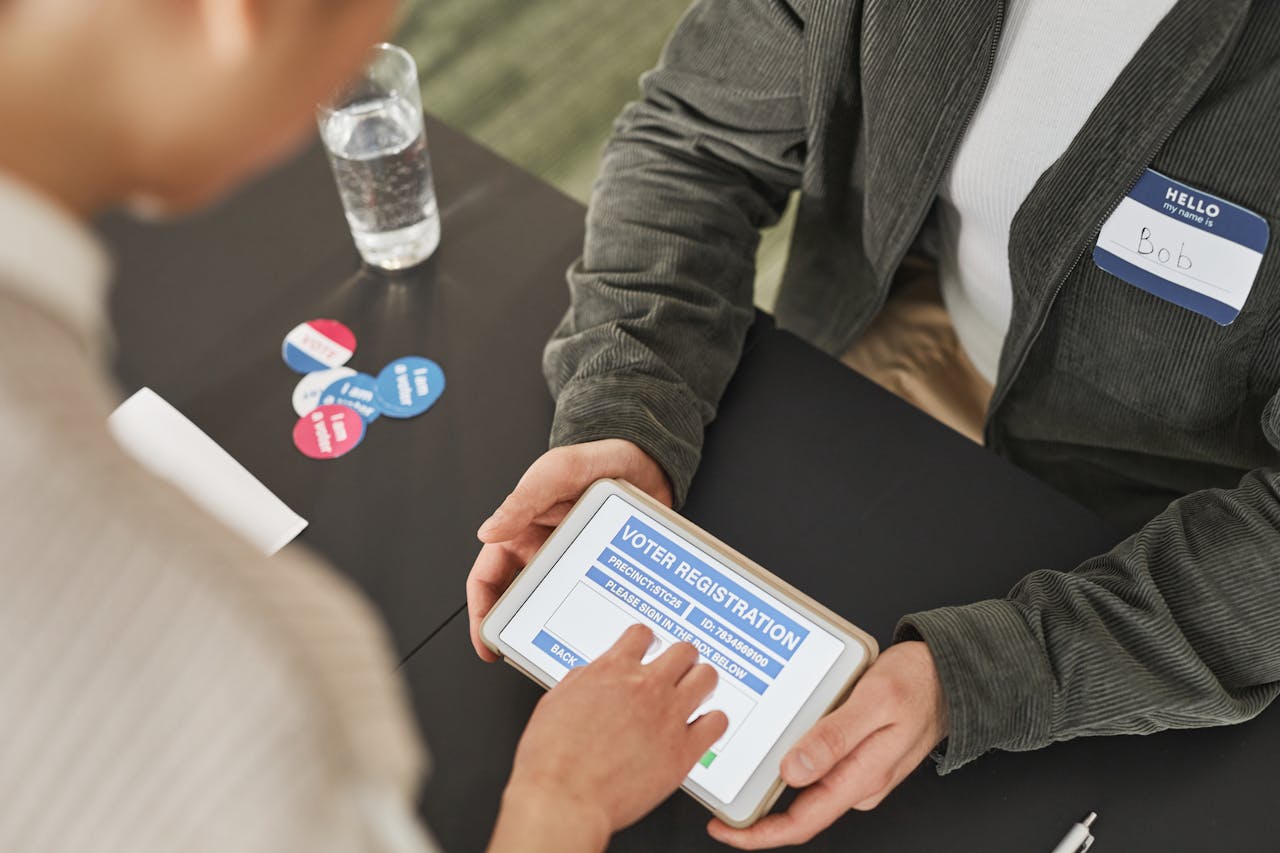 A person registers to vote using a tablet at a modern voting station.